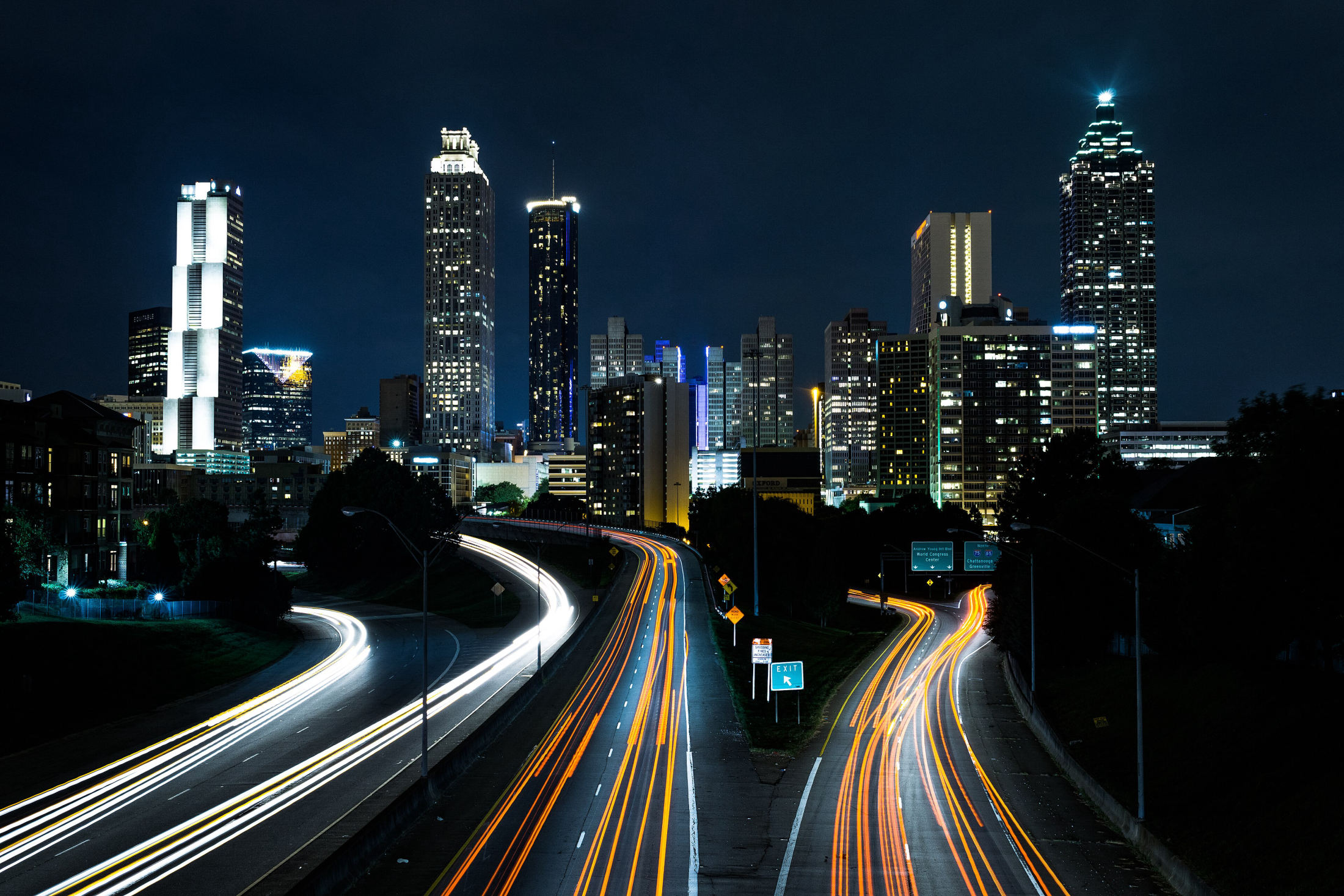 Atlanta skyline at night from the Jackson Street Bridge, with traffic light trails on Freedom Parkway